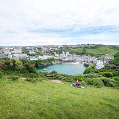 woman and dog on viewpoint above harbour and village of port isaac in cornwall
