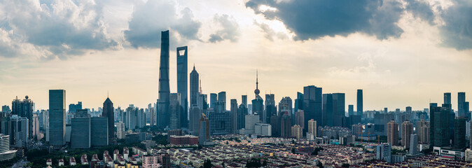 Fototapeta premium Famous skyline of a modern financial district with skyscrapers rising above traditional residential neighborhoods at dusk in Shanghai.