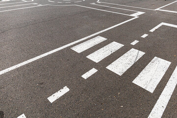 White crosswalk lines painted on dark asphalt, guiding pedestrians across a street or parking area.