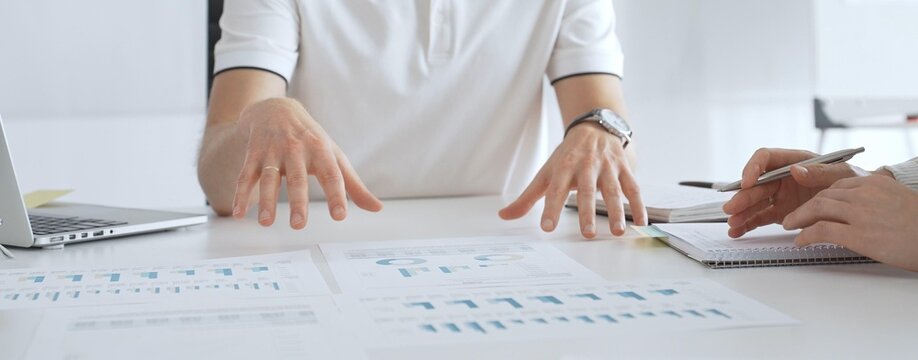 Business team reviewing financial charts, collaborating intently around conference table in contemporary workspace, sharing insights during strategic planning session in office meeting room