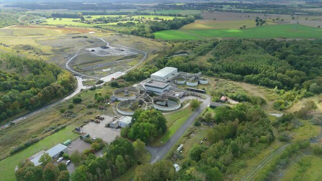 Aerial drone footage of a small water treatment plant, sewage wastewater sanitation and removal of contaminants, rural green landscape and rolling hills, Yorkshire England United Kingdom 