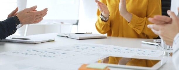 Business colleagues clapping hands after successful presentation or good news during a corporate meeting, celebrating achievement and success in office