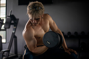 Athletic shirtless handsome young man, muscular young men are exercising with weights in a gym.
