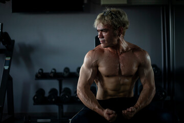 Athletic shirtless handsome young man, muscular young men are exercising with weights in a gym.
