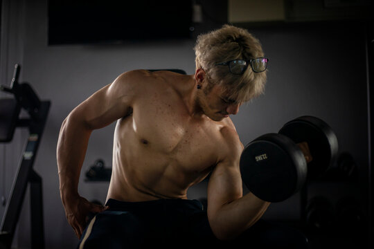 Athletic shirtless handsome young man, muscular young men are exercising with weights in a gym.
