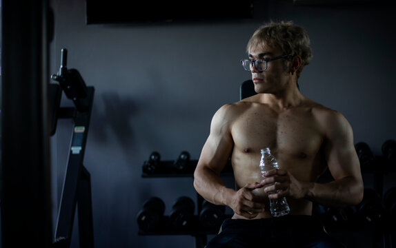 Athletic shirtless handsome young man, muscular young men are exercising with weights in a gym.
