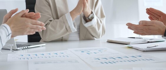 Professional business team clapping hands, celebrating successful presentation, displaying collaborative spirit and workplace enthusiasm in modern office setting