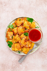 fried ravioli with parmesan cheese, served with red sauce and garnished with herbs, on a light background, no people,