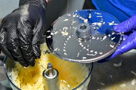 A woman's hands hold the vegetable grater blade of a food processor. - Powered by Adobe