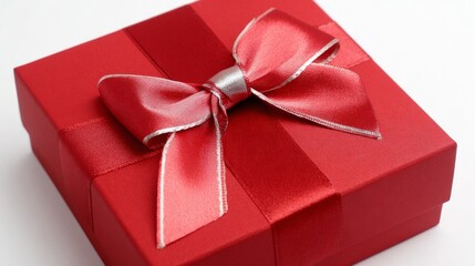 A red gift box adorned with a silver striped ribbon bow rests elegantly on a clean white surface,