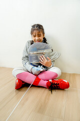 Vertical image of Asian girl with  fencing sport uniform sit on the floor and look sad also hold the mask after practice for competition.