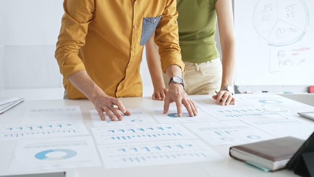 Professional team analyzing financial charts, collaborating intently around conference table in sleek, contemporary workspace. Business people concept - Powered by Adobe