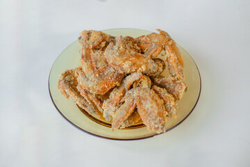 A close-up of a plate piled high with crispy fried chicken wings, showcasing the crunchy texture and delicious coating, ready to be eaten