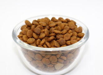 Dry balanced food for cats or dogs in a glass round bowl on a white background isolated.