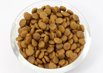 Dry balanced food for cats or dogs in a glass round bowl on a white background isolated. Top view