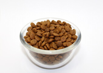 Dry balanced food for cats or dogs in a glass round bowl on a white background isolated.
