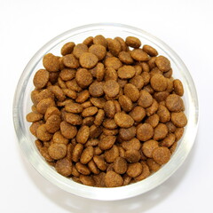 Dry balanced food for cats or dogs in a glass round bowl on a white background isolated. Top view
