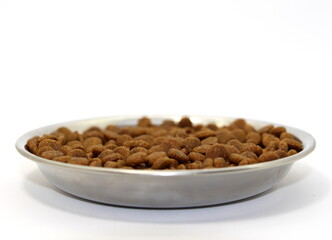 Dry balanced food for cats or dogs in a metal bowl on a white background.