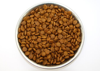 Dry balanced food for cats or dogs in a metal bowl on a white background.