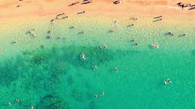 Vue a&eacute;rienne verticale d&rsquo;une plage aux vagues turquoise avec des personnes qui se baignent