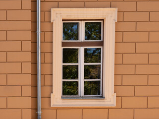 Classic white-framed window on beige brick wall
