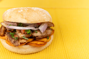 Peruvian Chicharrón Sandwich on Yellow Background