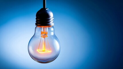 An incandescent light bulb glows brightly against a dark blue gradient background,