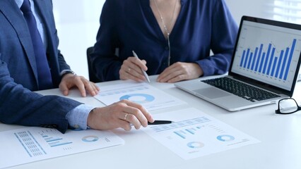Businesspeople reviewing financial data, analyzing charts and graphs, pointing at laptop screen during collaborative meeting. Business people and finance concept
