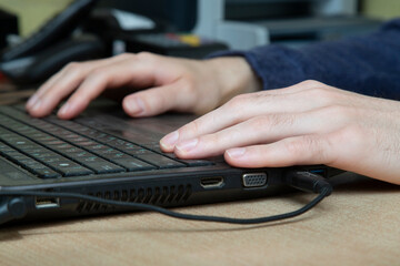 A man is working on a laptop. His hands are on the keyboard.