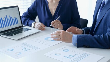 Businessman and business woman reviewing financial documents, gesturing over laptop screen, analyzing market charts for strategic corporate planning. Businesspeople concept