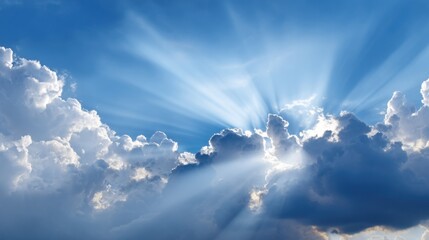 Sunlight streams through fluffy white clouds creating a stunning display of rays against a vibrant blue sky during the afternoon hours. Nature showcases its beauty.