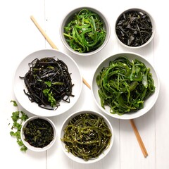 Assorted seaweed salads in white bowls on a white surface