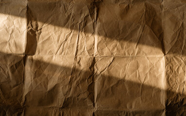 Texture background. Light casts intriguing shadows on crumpled brown paper surface.