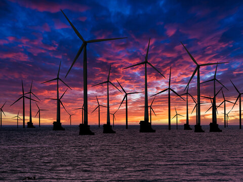 Windfarm or wind turbines off shore on sunset