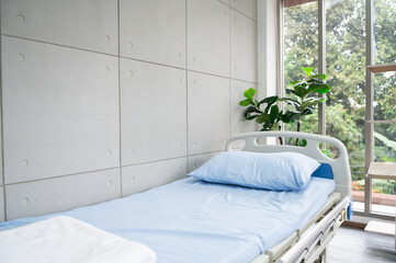 A hospital bed with blue sheets in a fresh and peaceful hospital room.