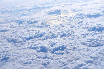 Expansive aerial view of dense cloudscape with sunlight reflection over tranquil sky horizon.