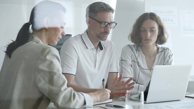 Professional team working together, reviewing digital analytics on laptop screen while strategizing corporate project details in modern workplace environment. Business people concept - Powered by Adobe