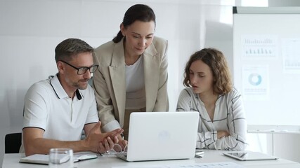 Business team collaborating on a project, analyzing data on a laptop during a productive office meeting, demonstrating teamwork and problem solving skills - Powered by Adobe