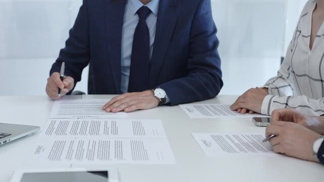 Professional businessman wearing tailored suit signing contract at sleek desk, sealing business agreement with collaborative partners in contemporary workspace