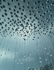 Abstract art of a modern art installation featuring numerous raindrop-like elements suspended in the air, creating a mesmerizing pattern. The overall mood is serene and thought-provoking.
