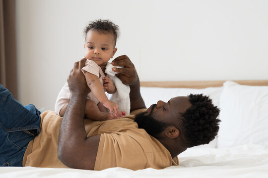 African American family and newborn baby. African American father takes care newborn baby by cleaning with towel at home