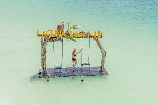 Young woman swinging over the turquoise waters of Kaan Luum Lagoon, Quintana Roo, Mexico. Relaxation and tropical adventure concept