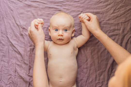 Newborn baby lying on a soft blanket while mother gently exercises the babys tiny limbs. Early development, bonding, and baby care concept