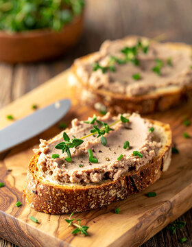 Appetizing crusty bread with smooth liver pate spread, fresh thyme and chives. Tasty food.