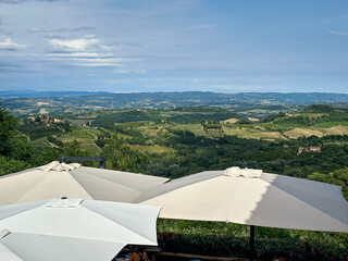 San Gimignano, Tuscany, Italy - 25.07.2025. Tuscan hills from old town - San Gimignano. Panoramic view on tile rooftop, vineyards, cypress trees and hills. Scenic Toscana from picturesque spot. Rural