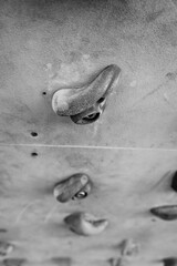 A detailed monochrome close-up of a climbing hold on an indoor bouldering wall, symbolizing the challenge and discipline of the sport