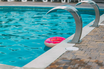 A vibrant pool scene with a donut float and water features.