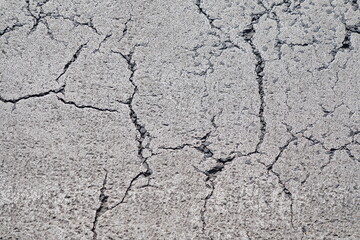Close-up macro view of weathered concrete pavement with intricate network of cracks and fissures