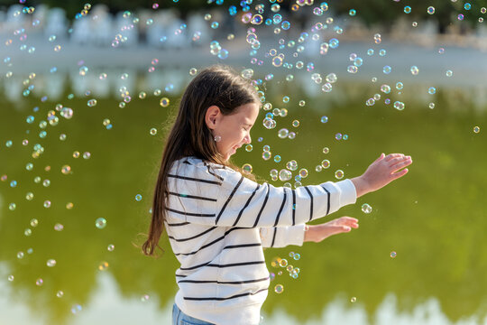 Girl playing with bubbles near a lake on a sunny day - Powered by Adobe