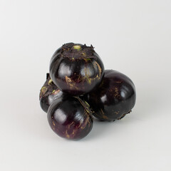 A pile of round eggplants on a white background